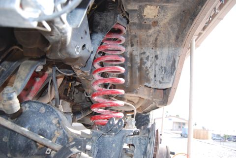1982 Ford Bronco - Undercarriage view showing a red coil spring and part of the differential assembly.