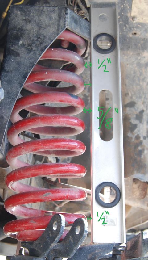 1982 Ford Bronco - A close-up view of a red coil spring with a level indicating measurements.