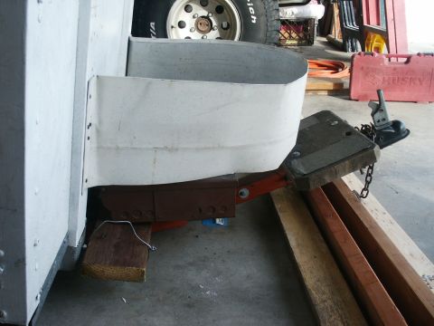 1990 Ford Bronco - A close-up view of a trailer's tongue and wheel well, supported by wooden blocks.