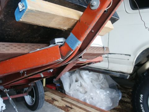 1990 Ford Bronco - A white vehicle's side is partially visible beneath an orange trailer frame, with a tire in the foreground.