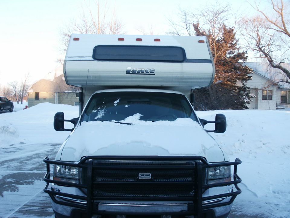 Truck with Lance camper in snow, front view. Has a brush guard