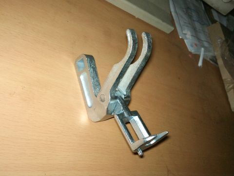 1998 Ford Crown Victoria - A valve spring compressor tool is shown on a wooden surface, with "SUPERMOTORS" text visible at the bottom right.