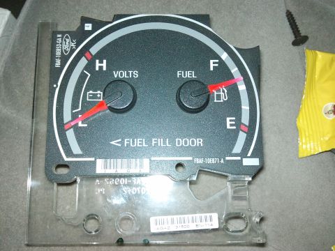 1998 Ford Crown Victoria - Close-up of a Ford instrument cluster, showing fuel and voltage gauges and text indicating fuel fill door location.