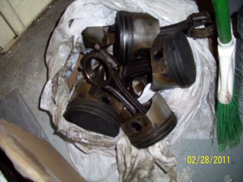 1995 Ford Probe - Used engine pistons and connecting rods are piled in a bag, with a broom visible on the right.