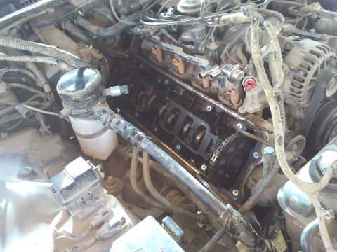 1998 Ford Crown Victoria - Engine compartment with valve cover removed, revealing internal engine components during maintenance.