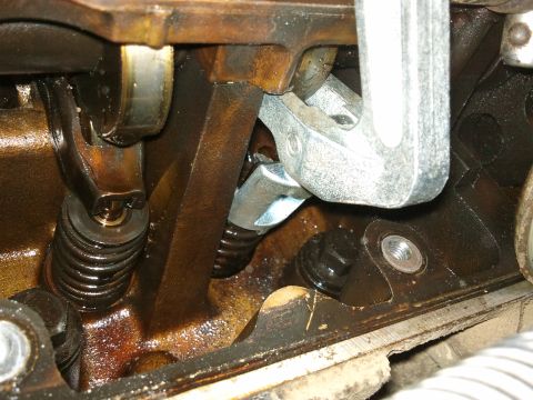 1998 Ford Crown Victoria - Mechanic uses a wrench to adjust a valve spring in an engine's valve train.