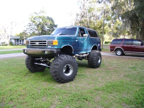 1978 Ford Bronco - This modified Ford Bronco features a significant lift kit and large off-road tires, with another vehicle in the background.