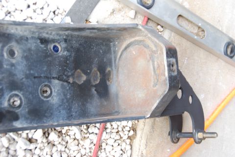 1982 Ford Bronco - A close-up view of a metal bracket, possibly from a vehicle, with visible bolts and signs of wear.