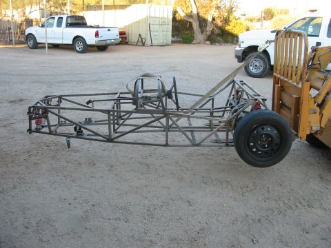 1993 Ford Taurus - A bare metal frame, possibly for a custom car or race car, is shown on a dirt lot.