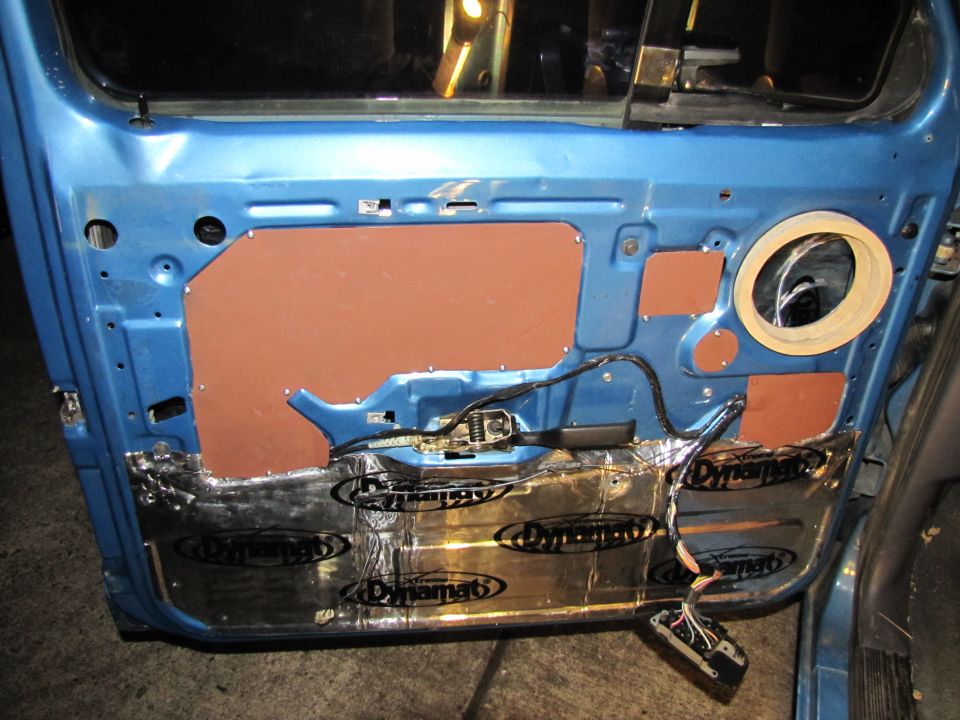 Interior of a blue car door with Dynamat sound deadening applied to the lower section and brown insulation panels