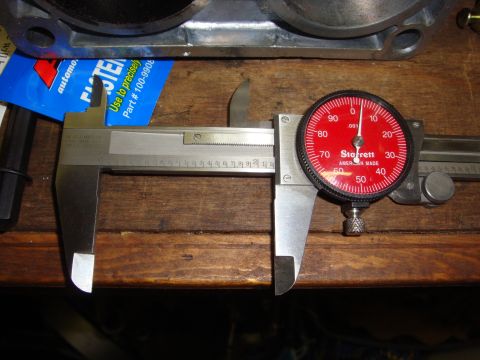 1989 Ford Bronco - A dial caliper is used to measure an engine component, with a package of fasteners nearby.