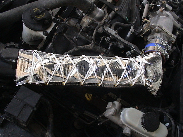 Engine bay with intake tube wrapped in silver heat-reflective sleeve laced with white cord