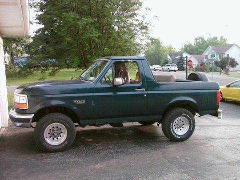 1993 Ford Bronco - Side view of a dark green 1993 Ford Bronco parked on a paved surface.