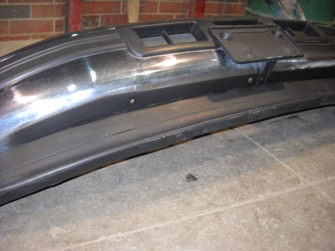 1993 Ford C-150 (Centurion Conversions) - A close-up view of a vehicle's front bumper, showing chrome accents and a license plate holder.