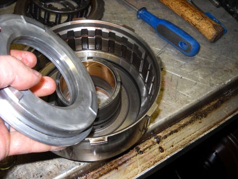 1993 Ford C-150 (Centurion Conversions) - Close-up of a transmission drum and a removed ring, with tools on a workbench.