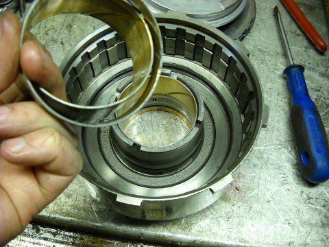 1993 Ford C-150 (Centurion Conversions) - Close-up of a disassembled automatic transmission drum, with a hand holding a component above it.