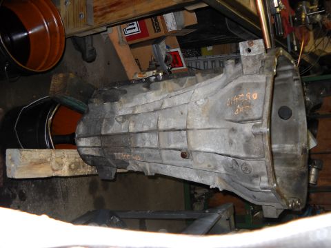 1993 Ford C-150 (Centurion Conversions) - A transmission part is shown in a workshop setting with various tools and boxes in the background.