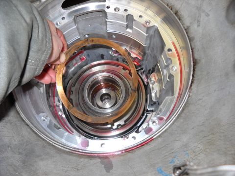 1993 Ford C-150 (Centurion Conversions) - Close-up of transmission internals with a hand holding a clutch disc during a rebuild.