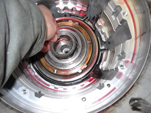 1993 Ford C-150 (Centurion Conversions) - Close-up of a transmission being rebuilt, showing internal components and a hand manipulating parts.