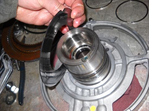 1993 Ford C-150 (Centurion Conversions) - A hand holds a metal ring above a disassembled automatic transmission part on a workbench.