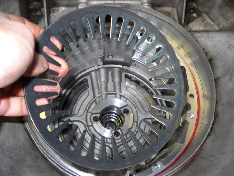 1993 Ford C-150 (Centurion Conversions) - Close-up of a transmission part being held by a hand during a rebuild process.