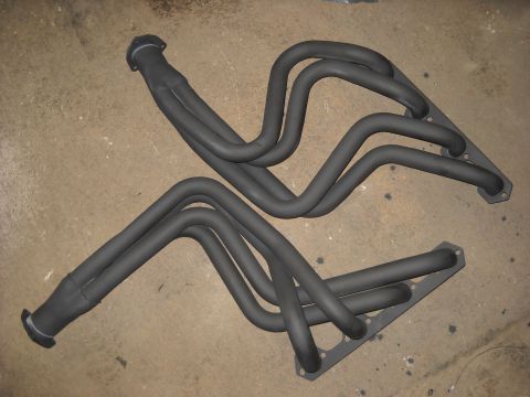 1993 Ford C-150 (Centurion Conversions) - A pair of black exhaust manifolds, each with four pipes, are displayed on a concrete surface.