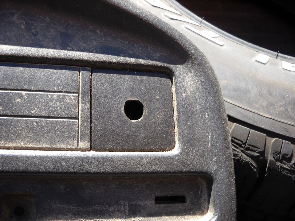 Dashboard interior with a circular hole and a tire visible