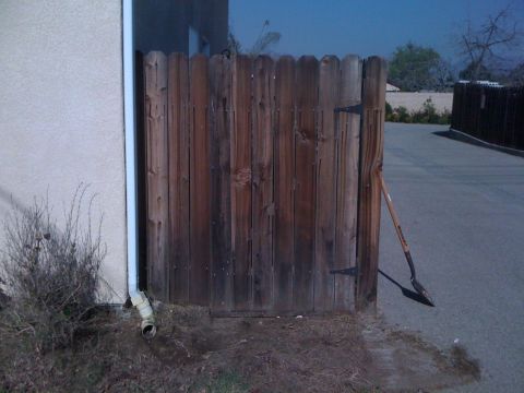 1968 Ford Mustang - A wooden gate stands closed next to a building, with a shovel resting against its post.