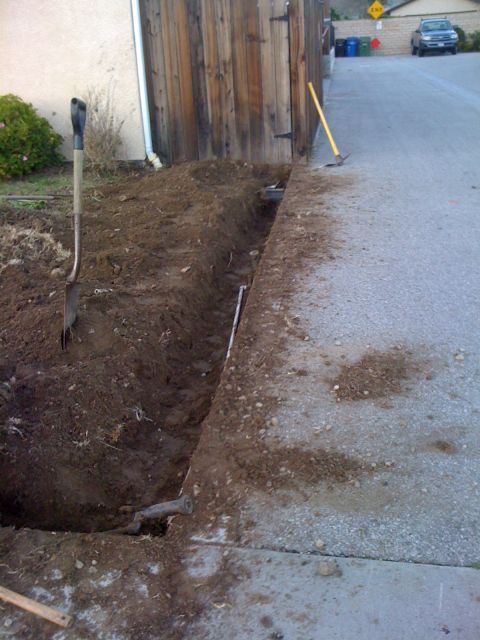 1968 Ford Mustang - A trench has been dug along the edge of a paved area, with tools left nearby.