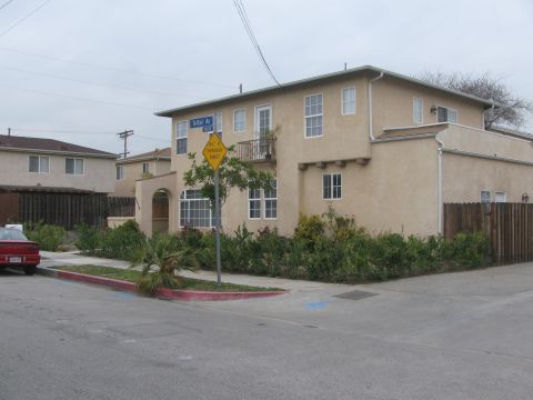 1968 Ford Mustang - Street view of apartment buildings and a red car parked on the side of the road.