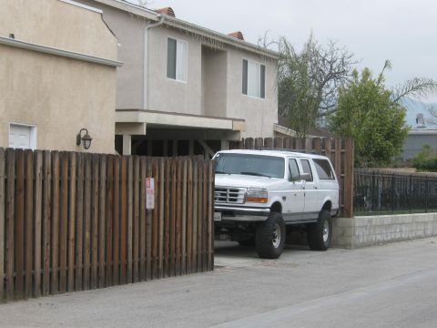 1968 Ford Mustang - A white SUV is parked in front of a house, with a wooden fence partially blocking the view.