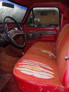 1995 Ford Bronco - The interior of a red truck shows a worn seat and dashboard details.