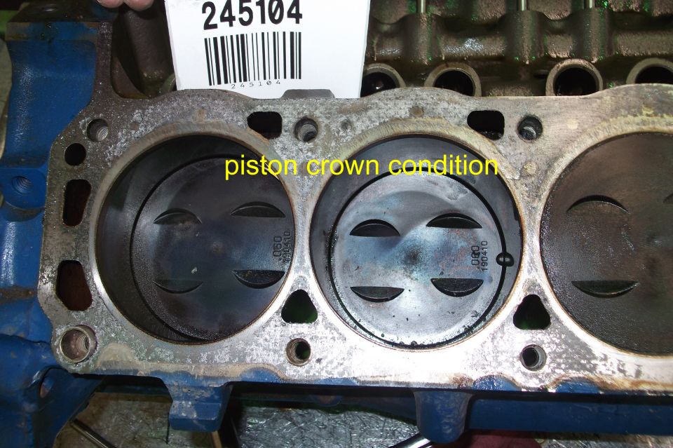 Engine block with pistons showing piston crown condition. Part number 245104 visible