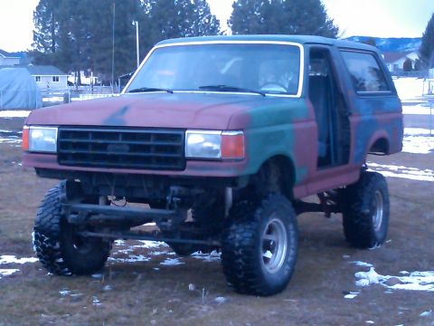 1988 Ford Bronco - Modified 1987 Ford Bronco with large off-road tires and camouflage paint scheme.