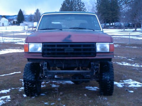 1988 Ford Bronco - This 1988 Ford Bronco features a lifted suspension and aggressive off-road tires, presented in a front-facing view.