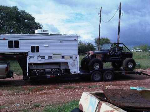 1967 Ford Mustang - An off-road vehicle is loaded onto a trailer with a camper, under a cloudy sky.
