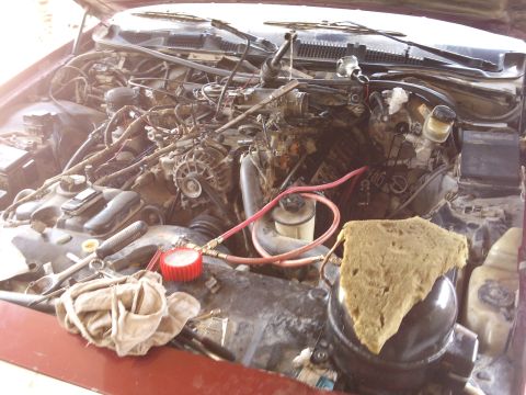 1998 Ford Crown Victoria - Engine bay with various tools and a pressure gauge laid out, suggesting maintenance work is in progress.