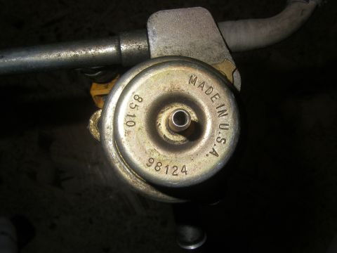 1990 Ford Bronco - A close-up view of a fuel pressure regulator, showing stamped text and part numbers.