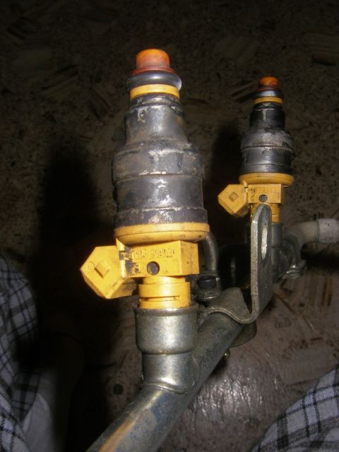 1990 Ford Bronco - Close-up of two automotive fuel injectors, likely part of a fuel system.