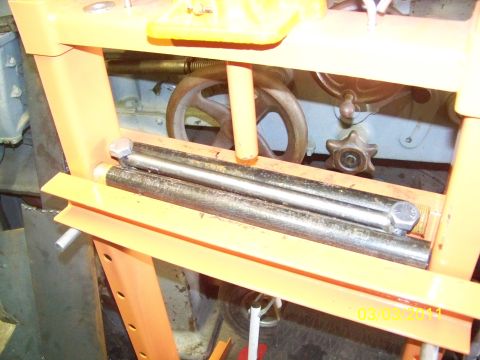 1989 Ford Bronco - Close-up of a metal press machine with two cylindrical rods positioned within its frame.
