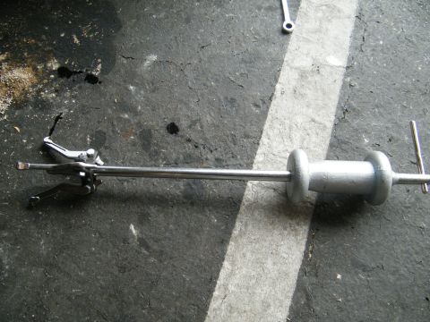 1982 Ford Bronco - Slide hammer puller tool with adjustable jaws on a concrete floor.