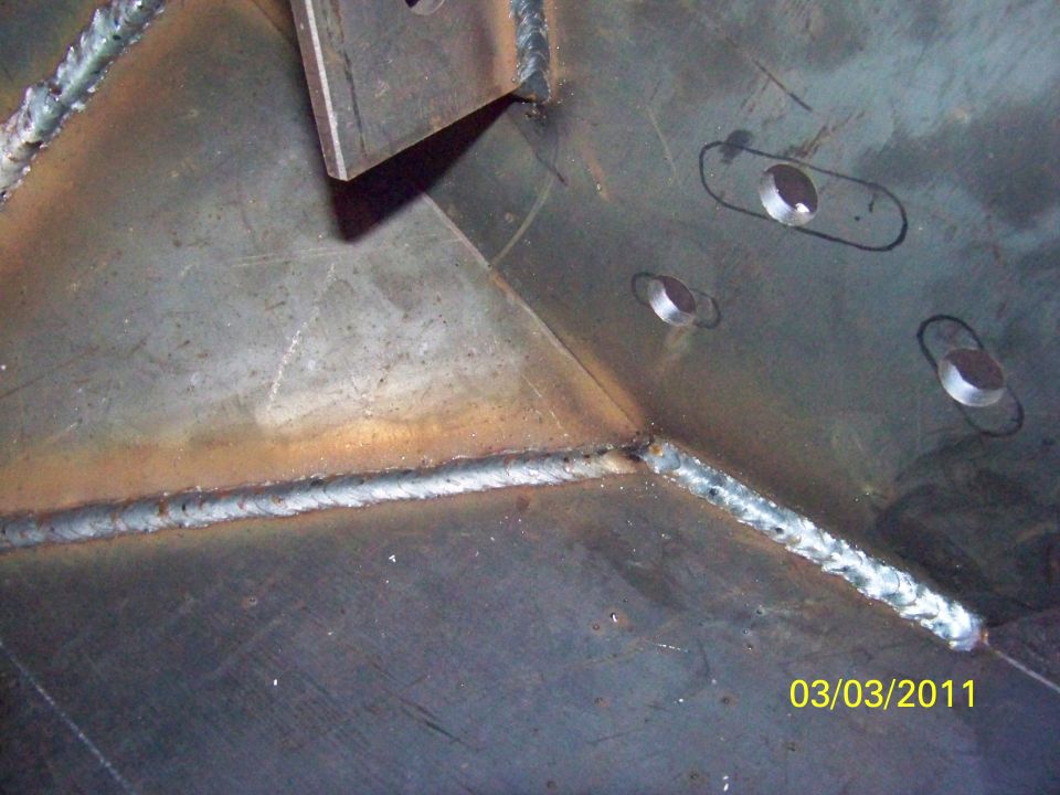 Close-up of welded metal plates with bolt holes. Date stamp reads 03/03/2011