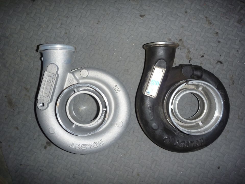 Two Holset turbo exhaust housings, one silver and one black, on diamond-plate floor