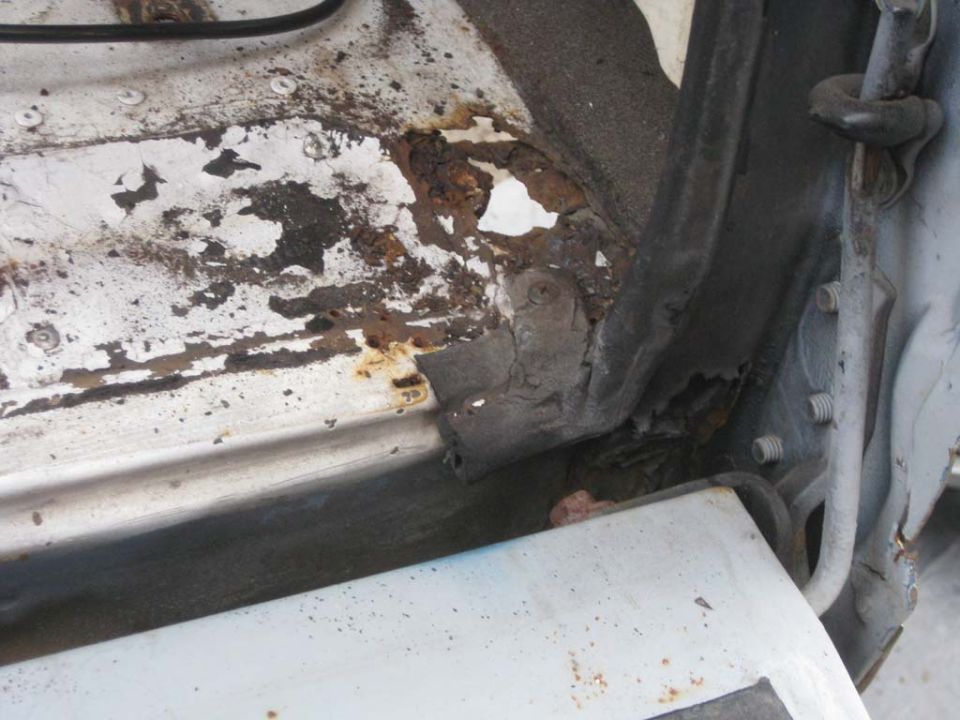 Rusted and flaking metal at a vehicle door sill and rocker panel