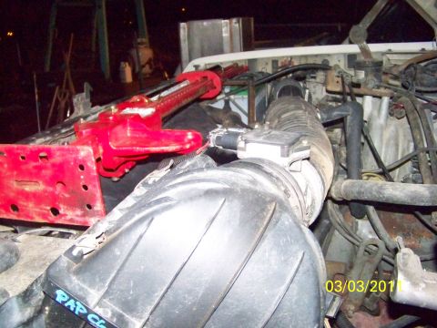 1989 Ford Bronco - Night shot into an engine bay showing a black plastic air cleaner box and ribbed intake tube with a mass air flow sensor clamped in the duc…