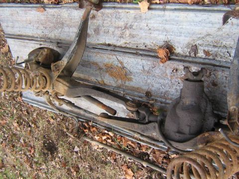 1994 Ford F-150 - Close-up view of various front suspension parts, likely from a truck, lying on a metal surface.