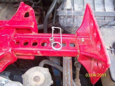 1989 Ford Bronco - Close-up of a red metal bracket with a safety pin, likely a vehicle part.