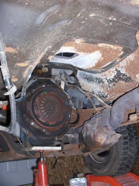 1994 Ford F-150 - The underside of a vehicle shows the transmission and exhaust components, with a jack providing support.