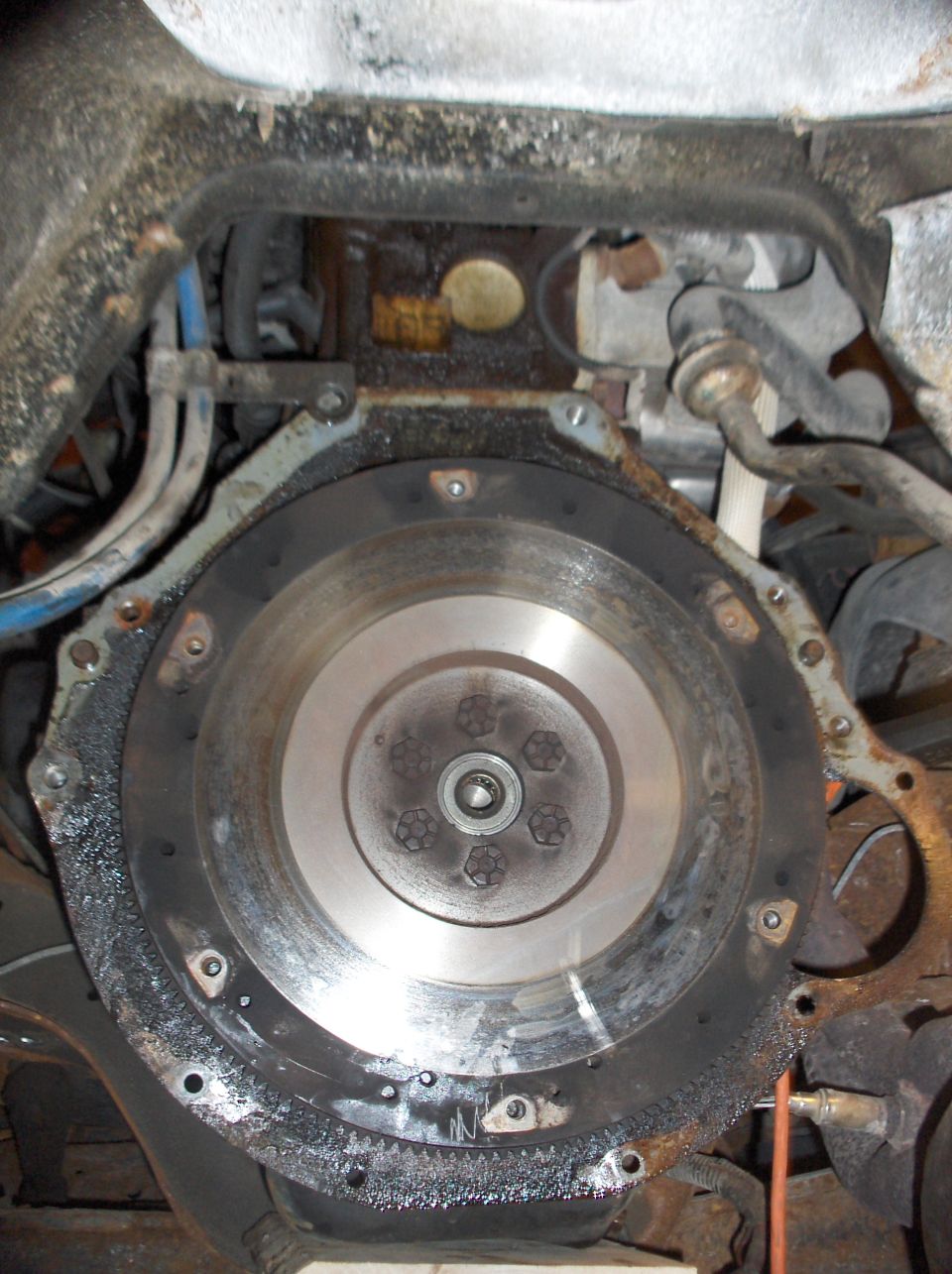Engine flywheel with visible bolts and surrounding metal components