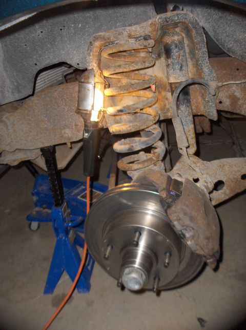1994 Ford F-150 - Vehicle suspension component with coil spring and brake rotor, supported by a jack.